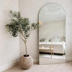 Staande boogspiegel verzilverd blank in een lichte slaapkamer