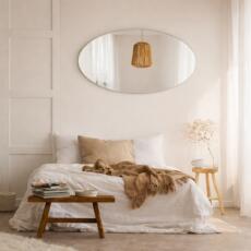 Ovale spiegel in een lichte slaapkamer