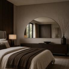 Halfronde spiegel boven een dressoir in een luxe slaapkamer.