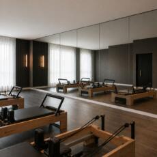 Pilatesstudio met grote verzilverd blanke spiegelwand en houten reformers.