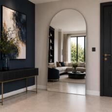 Grote toogspiegel in een moderne entree met zicht op een luxe woonkamer.