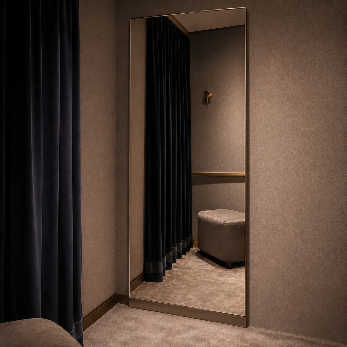 Luxe passpiegel in een stijlvolle paskamer met donker gordijn en poef.