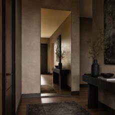 Gouden wandspiegel in een chique entreehal met donkere houttinten, zwarte sidetable en warme luxe uitstraling.