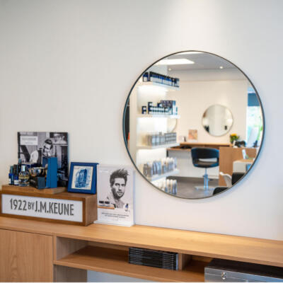 Een ronde kapperspiegel bevestigd aan de muur van een kapsalon