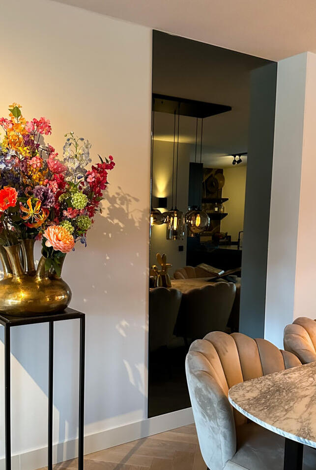 Een grijze wandspiegel in de woonkamer, geplakt aan de muur