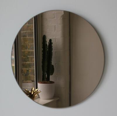 Een brons gekleurde spiegel aan de muur, in ronde vorm